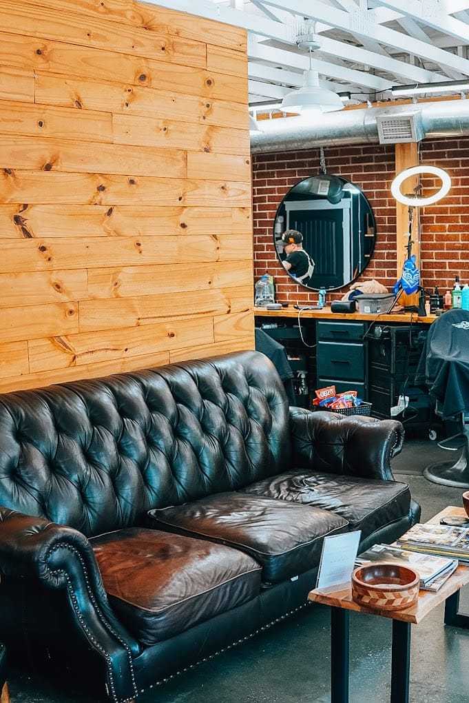 Cozy barbershop interior with leather sofa, mirror, and grooming stations.