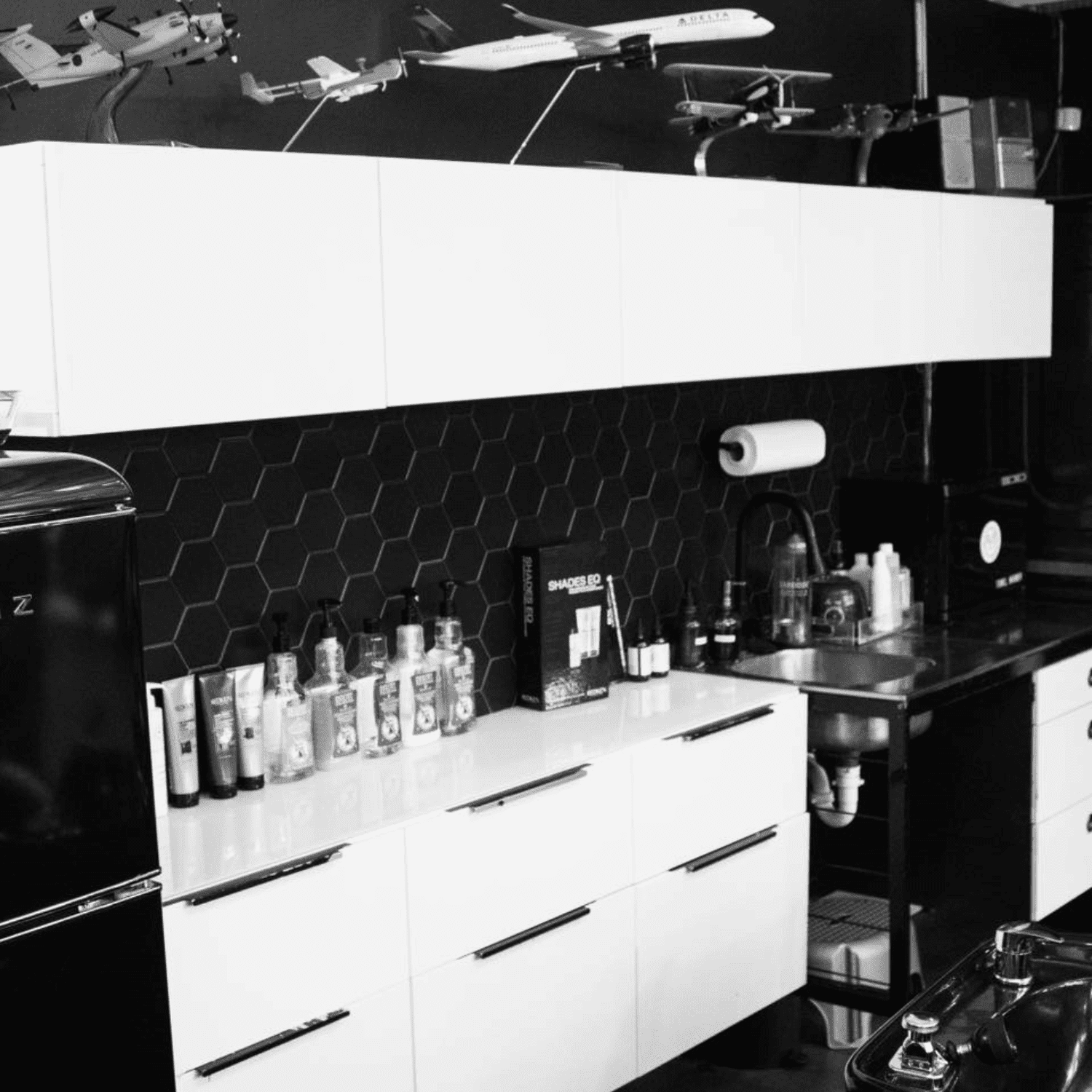 Model airplanes displayed on shelves above a modern kitchen with black and white decor.