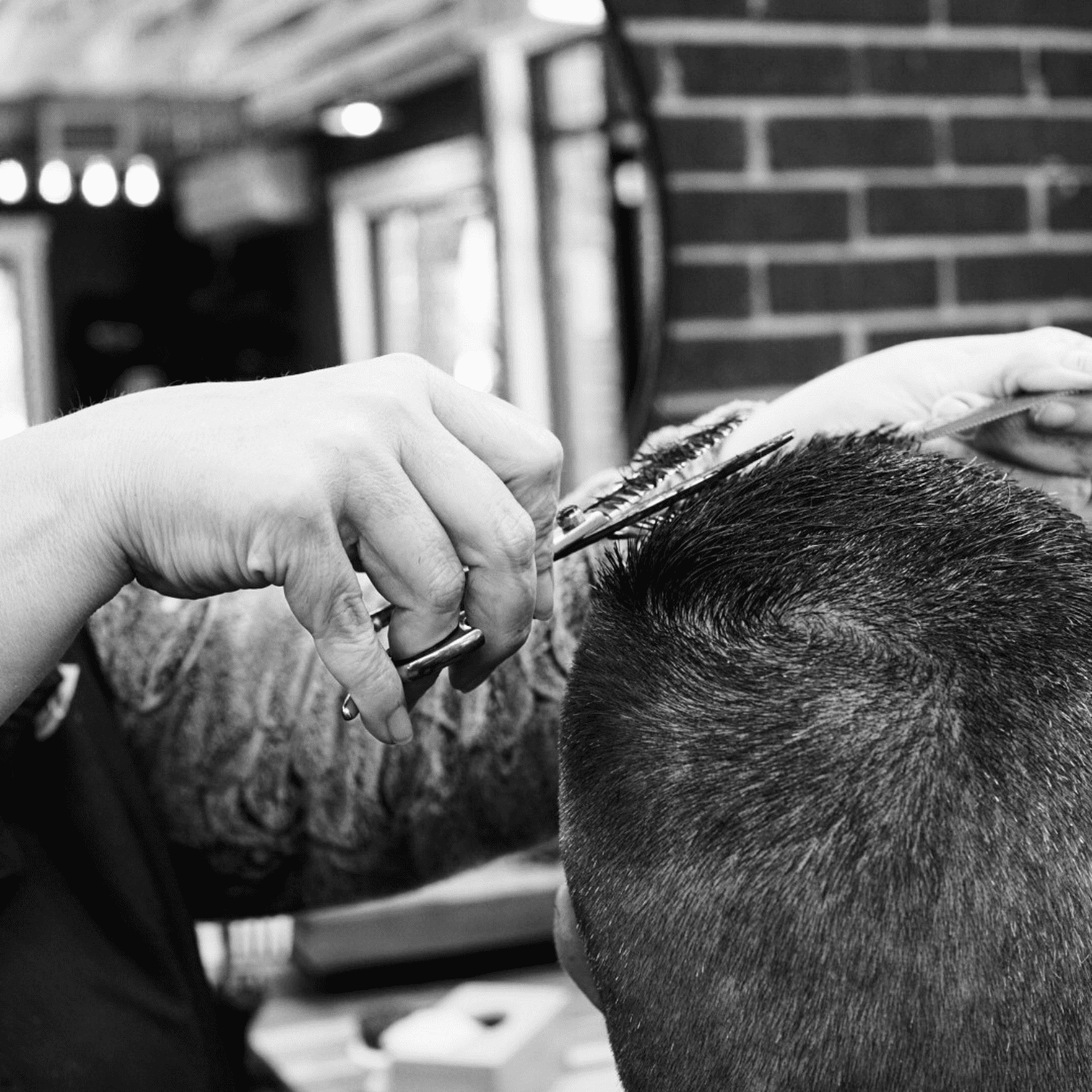 Barber giving a haircut with clippers and scissors in a barbershop.