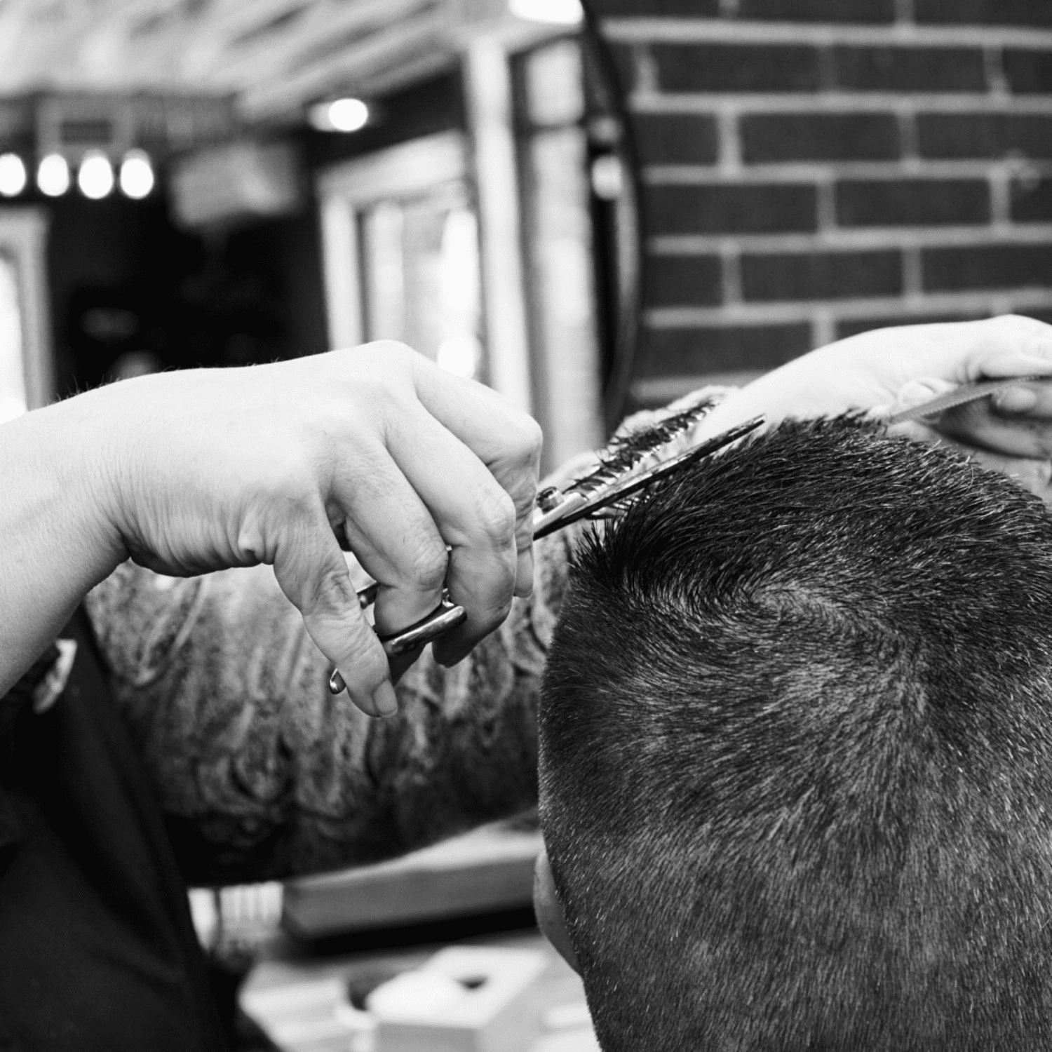 Barber giving a haircut with clippers and scissors in a barbershop.